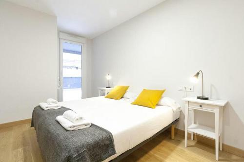 1 dormitorio blanco con 1 cama grande con almohadas amarillas en Four Seasons-Centro.Wifi.Terraza, en San Sebastián
