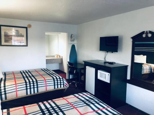 a hotel room with a bed and a television at Meridian Inn Oklahoma City Airport in Oklahoma City