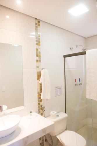 a bathroom with a sink and a toilet and a shower at Grand Enio Hotel e Cantina in Varginha