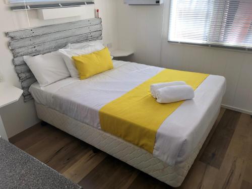 Palm Beach Caravan Park في سانكشوري بوينت: غرفة نوم بسرير كبير ومخدات صفراء وبيضاء