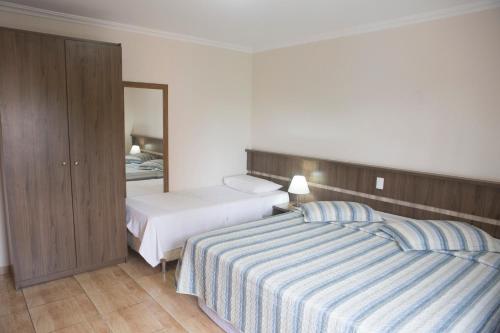 a hotel room with two beds and a mirror at Grand Enio Hotel e Cantina in Varginha