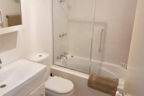 a white bathroom with a toilet and a shower at Seadreams, Maroubra in Sydney