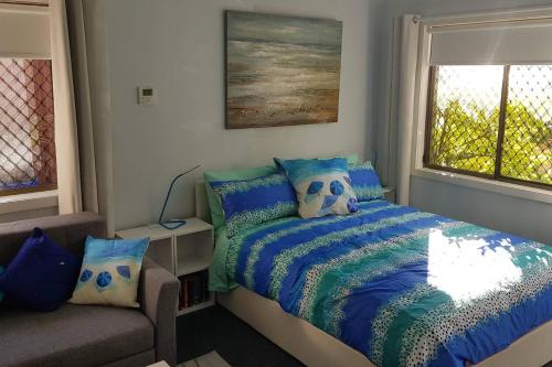 a bedroom with a bed and a couch and a window at Seadreams, Maroubra in Sydney