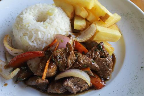 a plate of food with meat and vegetables and rice at Casa Andina Standard Nasca in Nazca