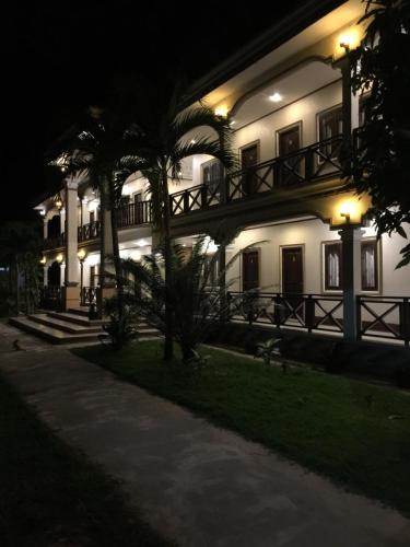 a large white building with a balcony at night at Lebijou Guesthouse - Konesavath in Don Det