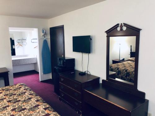 a hotel room with a dresser and a mirror at Meridian Inn Oklahoma City Airport in Oklahoma City