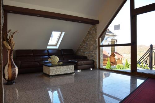a living room with a leather couch and a large window at Apartman Sladjana Premier 12 Milmari in Kopaonik