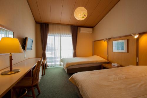 a hotel room with two beds and a desk at Hotel Kikori in Hida