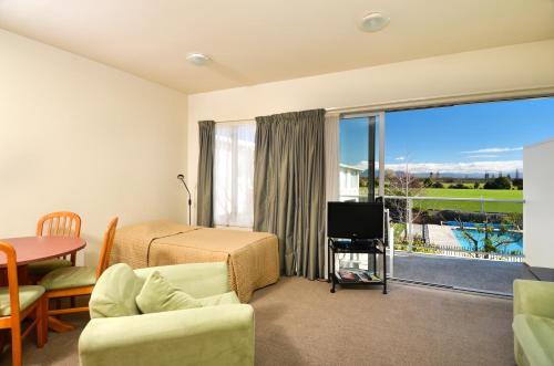 a bedroom with a bed and a television and a balcony at Parkside Motel in Richmond