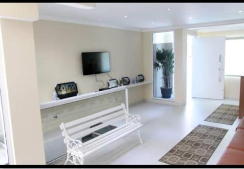 a living room with a white bench and a tv at SETTA'S HOSTEL in Sao Paulo