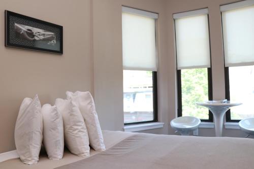 um quarto com uma cama com almofadas brancas e janelas em Furnished Studio in Downtown Boston #35 em Boston