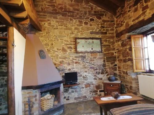 a room with a stone wall with a fireplace at Apartamentos rurales Casa Do Cabo in Vega de Logares