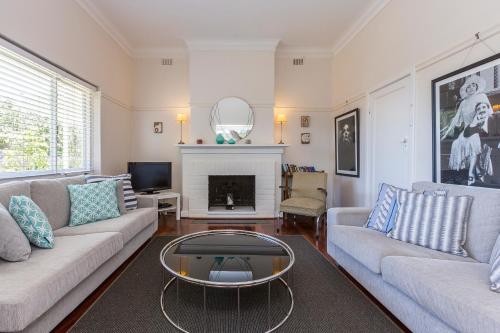a living room with two couches and a fireplace at Cottesloe Bel-Air Apartment in Perth