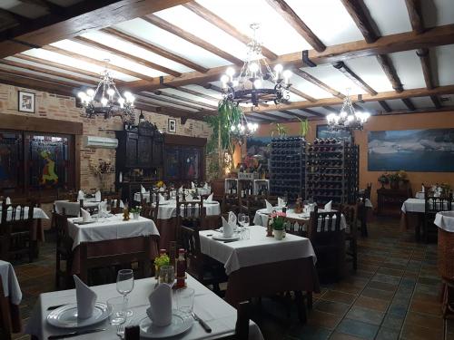 マドリガル・デ・ラ・ベラにあるHosteria Doña Conchiの白いテーブルと椅子、シャンデリアのあるレストラン