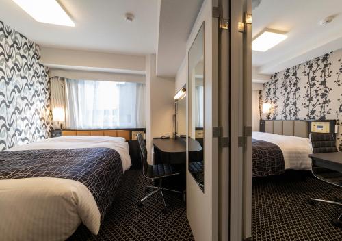 a hotel room with two beds and a desk at APA Hotel Yodoyabashi Kitahama Ekimae in Osaka