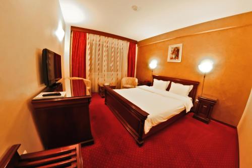 a hotel room with a bed and a television at Hotel Bavaria in Craiova