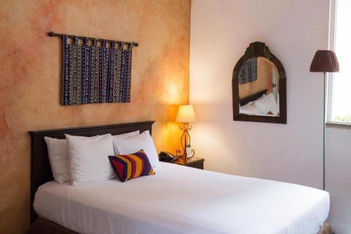a bedroom with a bed and a mirror at Hotel Ciudad Vieja in Guatemala