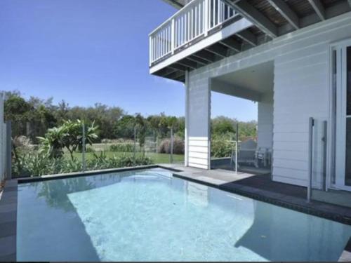 a swimming pool in front of a house at Serenity Beach Retreat in Casuarina