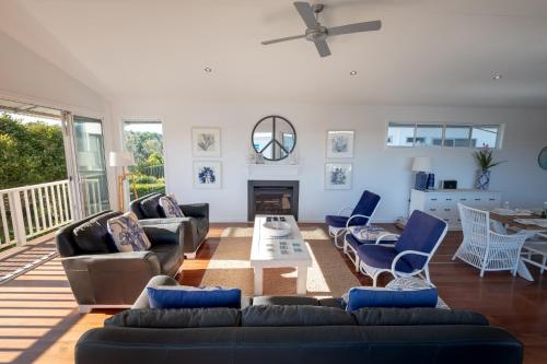 a living room with a couch and chairs and a fireplace at Serenity Beach Retreat in Casuarina