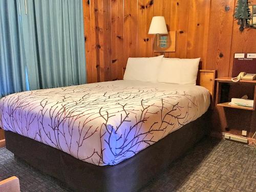 a bedroom with a bed with a purple and white comforter at Park Motel and Cabins in Florence