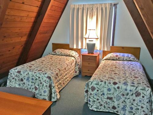 a bedroom with two beds and a lamp on a table at Park Motel and Cabins in Florence