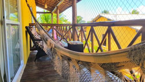 a hammock on a balcony with a fence at Linda Casa de Praia em Itacimirim in Itacimirim