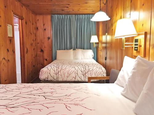 two beds in a hotel room with wooden walls at Park Motel and Cabins in Florence