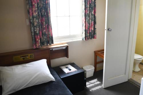 a bedroom with a bed and a window and a window istg at Castlereagh Hotel in Dubbo