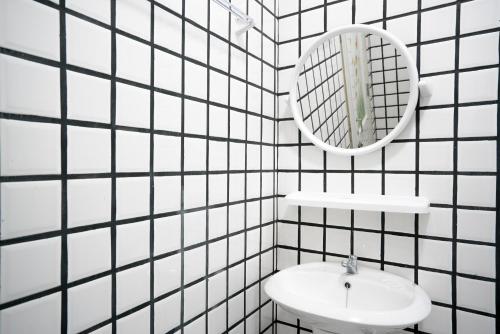 a white tiled bathroom with a sink and a mirror at Dhub Hostel Donmueng in Bangkok