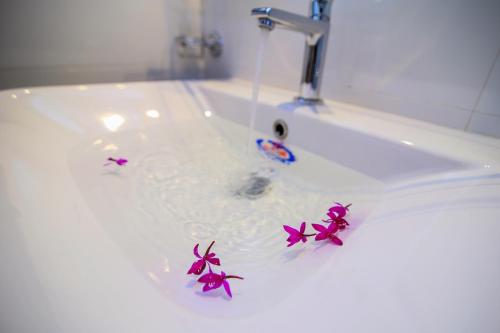 a bathroom sink with purple flowers in the water at Villa Seagull in Hikkaduwa