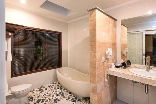ein Badezimmer mit einer Badewanne, einem Waschbecken und einem WC in der Unterkunft Taluh Bebek Ubud Private Villas in Ubud