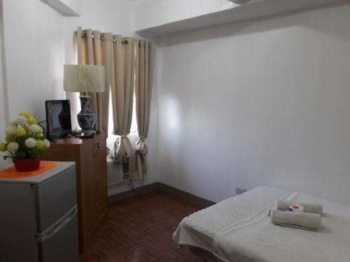 sypialnia z łóżkiem i telewizorem w pokoju w obiekcie EKONUMI ROOMS at Moonwalk Paranaque w mieście Manila