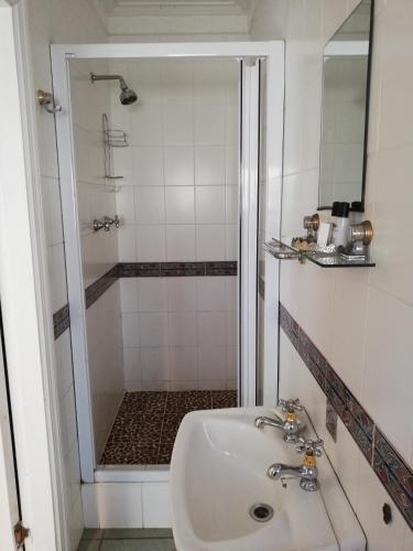 a white bathroom with a sink and a shower at Fairway Guest House in Durban