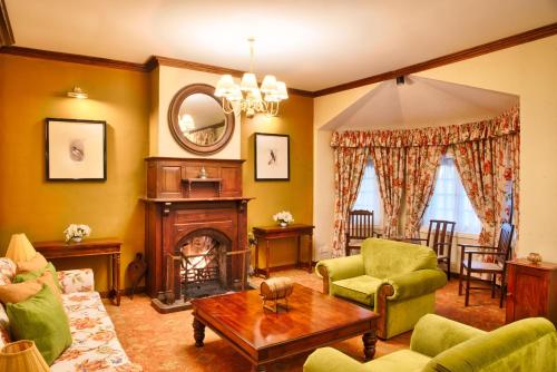 a living room with a fireplace and green furniture at Jetwing Oatlands Bungalow in Nuwara Eliya