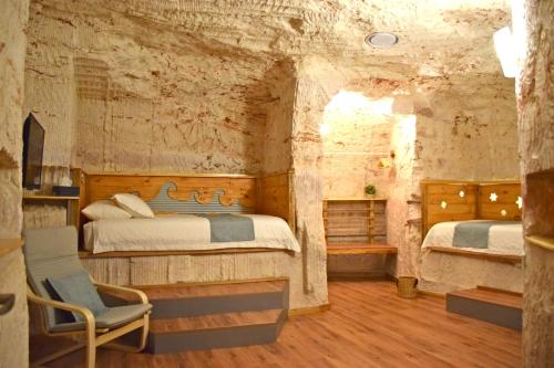 1 dormitorio con 2 camas y 1 silla en Dug Out B&B en Coober Pedy