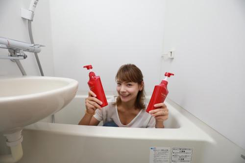 a woman is holding up two red toothbrushes at IBASHO ShibuyaDogenzaka810 in Tokyo