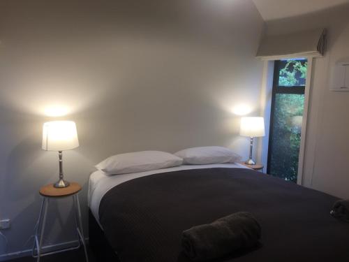 a bedroom with a bed with two lamps and a window at Black Beech House with Stunning Outdoor Bath in Lake Tekapo