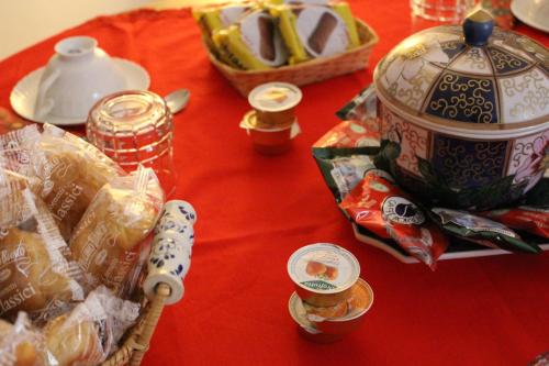 a red table with a tea pot and a basket of food at B&B 'A Puteca in San Marco dei Cavoti