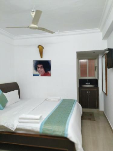a bedroom with a bed with a picture on the wall at Aum Hotel in Puttaparthi