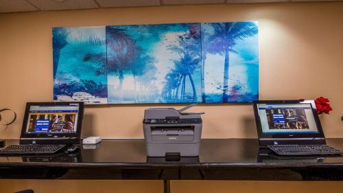 three laptops and a printer on a desk with a wall at Best Western Plus Bradenton Hotel & Suites in Bradenton