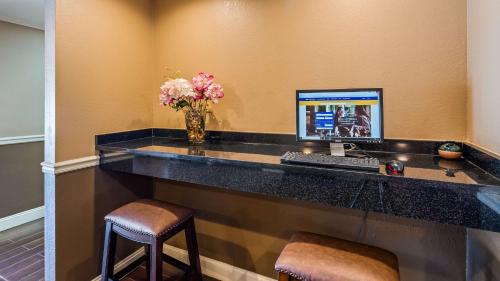 a desk with a computer and a vase of flowers at Best Western Shelbyville Lodge in Shelbyville
