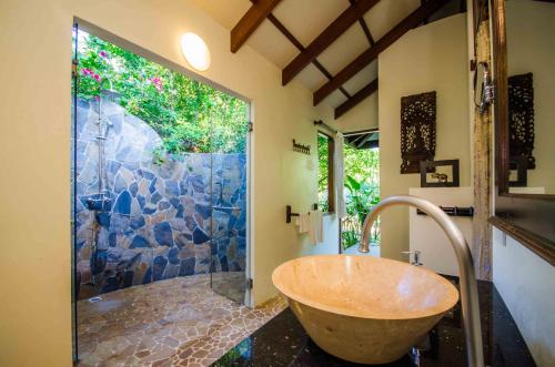 a bathroom with a large stone shower with a wooden tub at Koh Jum Beach Villas "A member of Secret Retreats" in Ko Jum