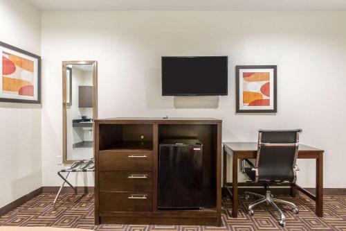 a room with a desk and a television on a wall at Scottish Inns & Suites Spring - Houston North in Spring