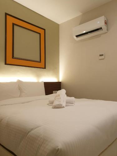 a bedroom with a white bed with a air conditioner at Ants Hotel in Kangar
