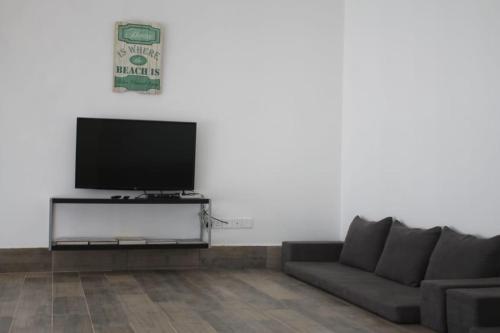 a living room with a couch and a flat screen tv at Ash Villa in Al Ashkharah