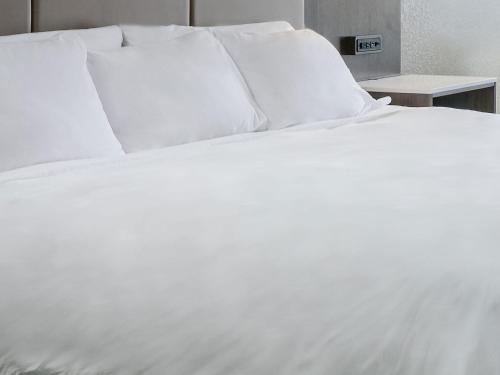 a white bed with white sheets and pillows at Radisson Kingswood Hotel & Suites, Fredericton in Fredericton