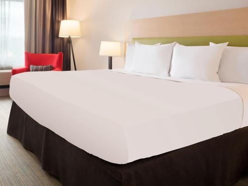 a large bed in a hotel room with a red chair at Country Inn & Suites by Radisson, Duluth North, MN in Duluth