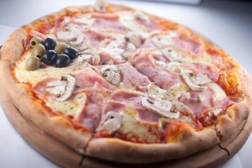 a pizza with ham and olives on a table at Hotel Moskva in Budva