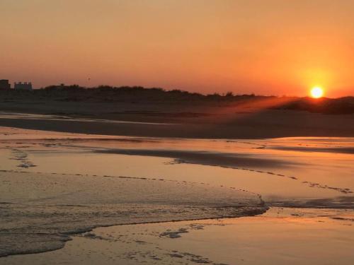 a sunset on the beach with the tide coming in at Ash Villa in Al Ashkharah