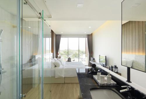 a bathroom with a bed and a glass shower at Phurinda Residence in Sara Buri